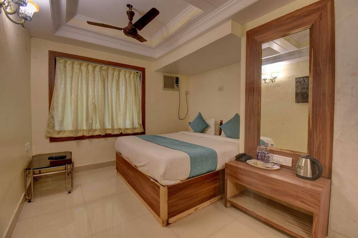 A bedroom with a bed, bedside table, mirror, and a ceiling fan.
