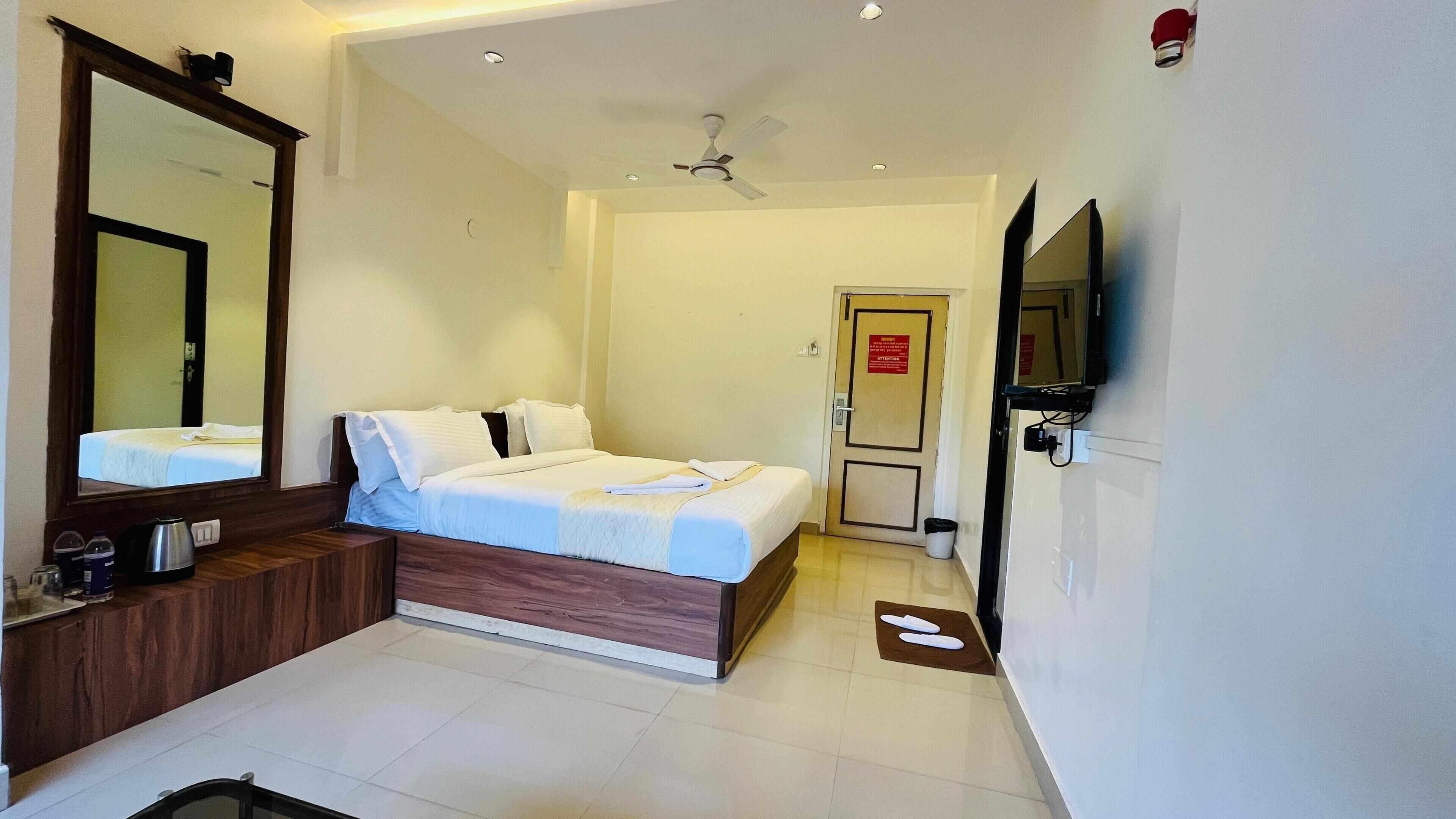 Ein Hotelzimmer mit einem Bett, einem großen Spiegel, einem Fernseher und einem Deckenventilator.