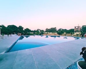 An outdoor swimming pool with a clear blue water surface, surrounded by potted plants and trees. - The Vaag Udaipur A Luxury Pool Villa in Udaipur (Udaipur)