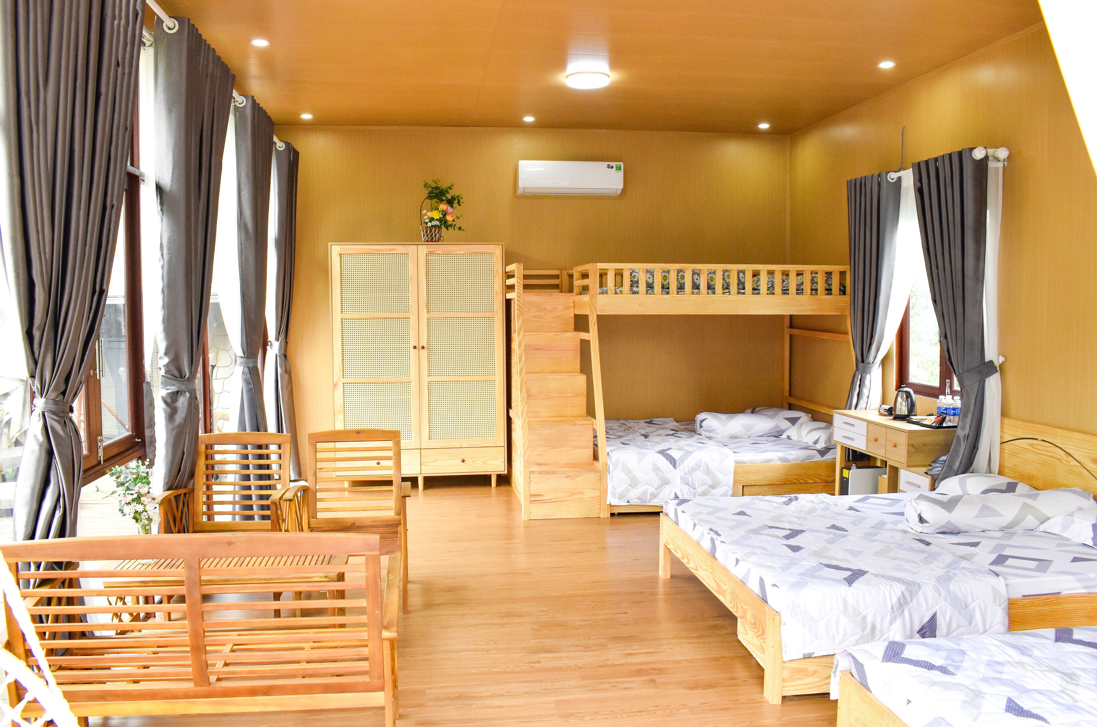 Une chambre avec des lits superposés, un bureau en bois, une chaise et une armoire.