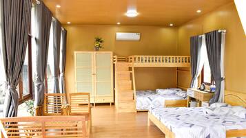 Une chambre avec des lits superposés, un bureau en bois, une chaise et une armoire.