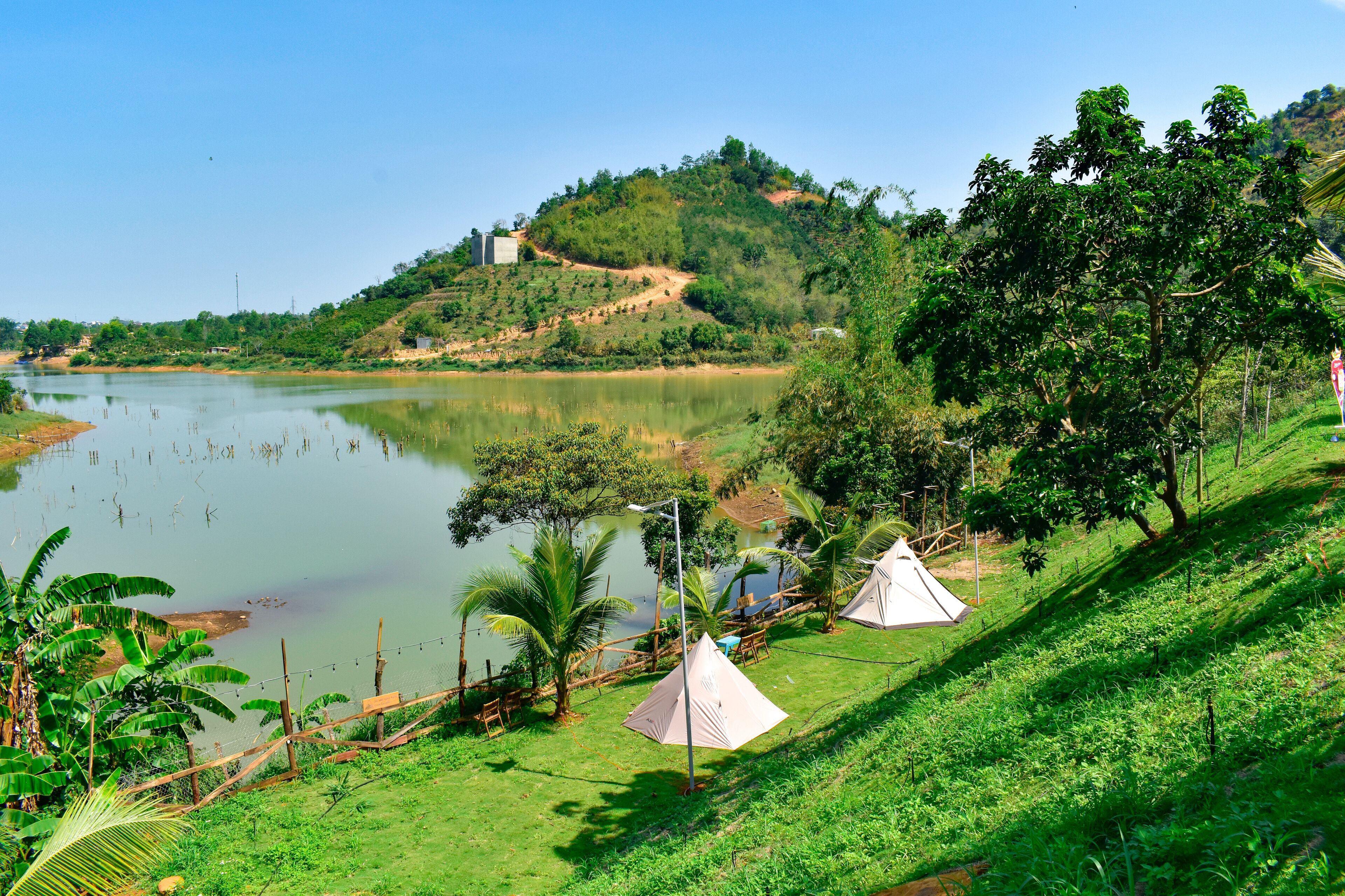 A riverside campsite with tents and lush greenery.