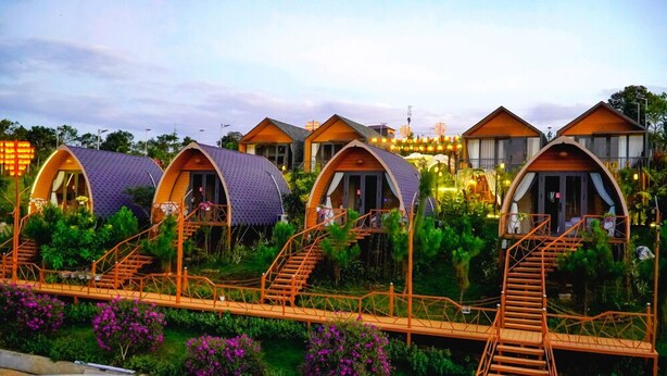 A row of dome-shaped cabins with wooden staircases leading to each unit. - EVA VILLAGE (Dong Gia Nghia)