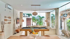 Un comedor moderno con mesa de billar, muebles de madera y un frutero.