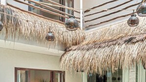 Un área de piscina con sillas de descanso, una puerta de cristal y una estructura de techo de paja.