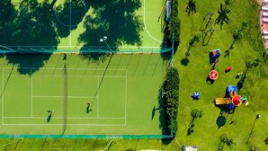 Ilmakuva tenniskentästä, jota ympäröivät puut ja jonka läheisyydessä on leikkikenttä.