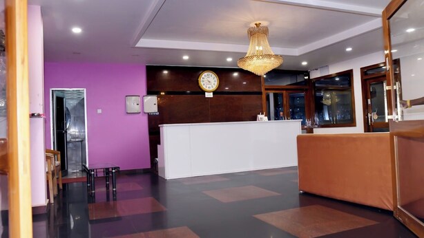 A reception area with a reception desk, a clock, and a chandelier. - Hotel Pardesi Cardo (Saharsa)