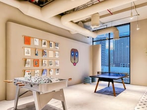 Enjoy a game night in this vibrant room, featuring a foosball table and ping pong table, surrounded by artwork and city views.