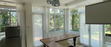 A modern kitchen with a central island, pendant lights, and large windows.