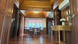 A wooden-paneled room with a dining area, a chandelier, and a fan. - Blooming Village by Aforetime (Koh Samui)