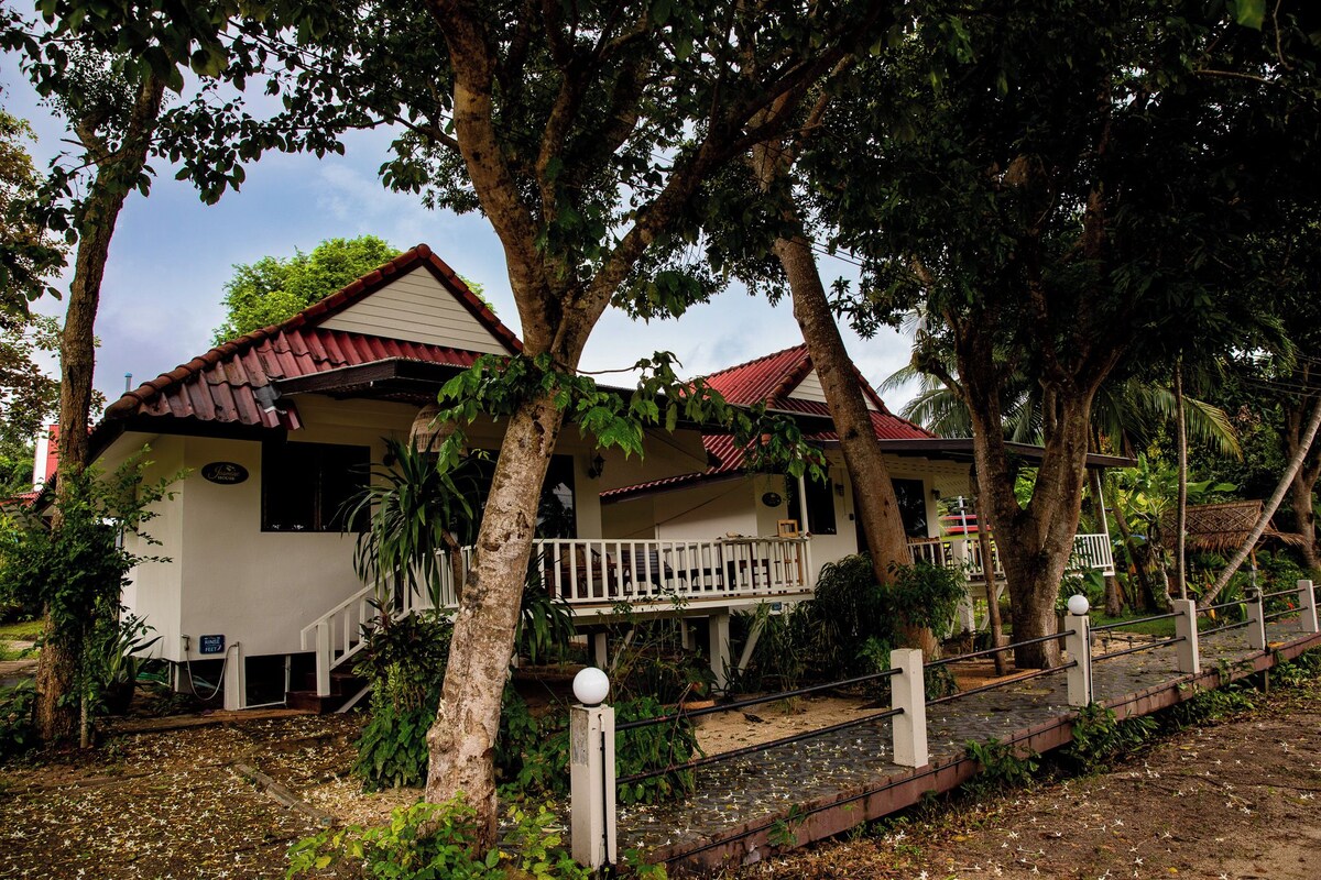 A house with a red roof, surrounded by trees and a small garden.