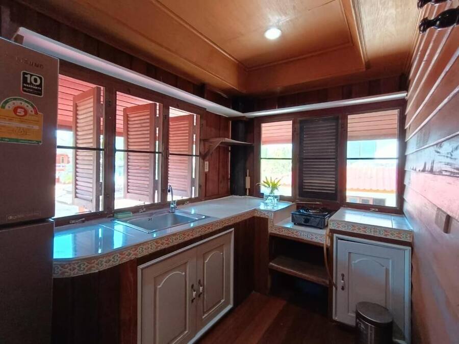 A compact kitchen with wooden cabinets, a refrigerator, and a sink.