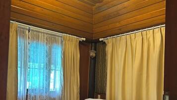 A wooden-paneled room with a bed, curtains, and a chandelier.