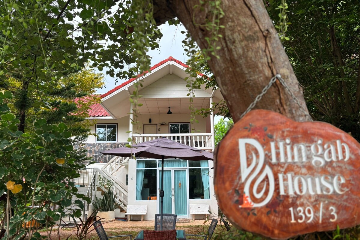 A house with a porch, a dining area with chairs, and a sign that reads 'Dingab House 139/3'.