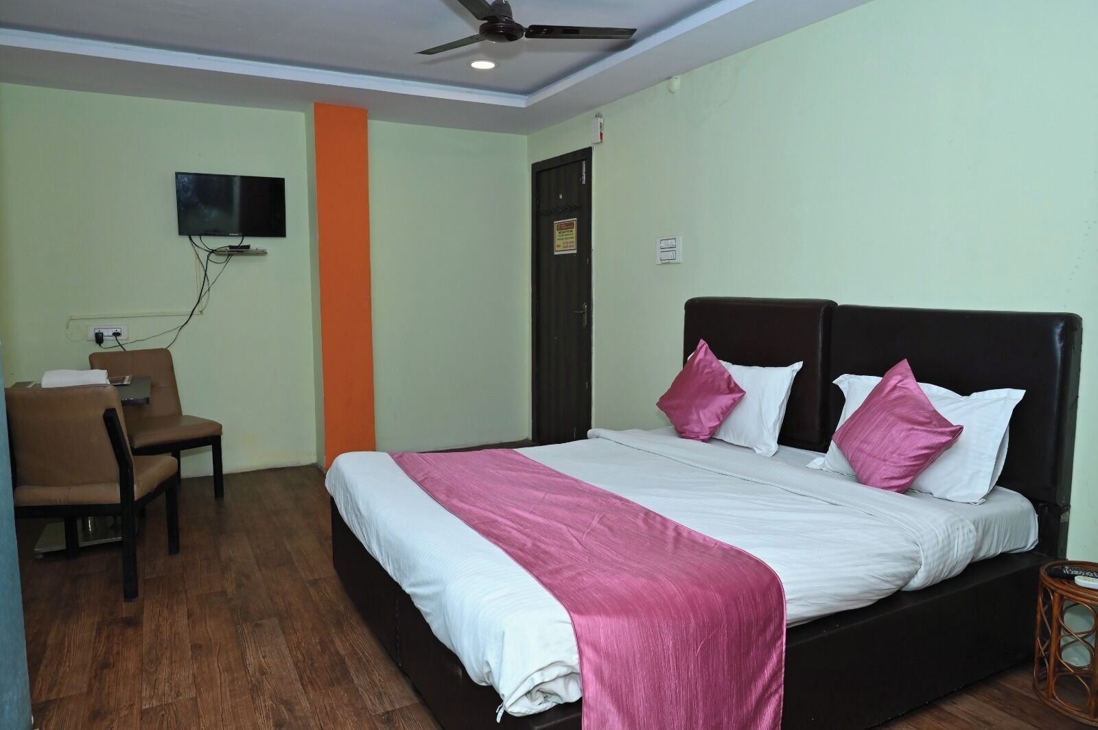 A hotel room with a bed, a desk, a chair, and a television mounted on the wall.