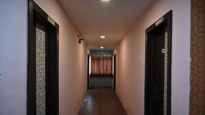 A narrow hallway with wooden flooring, doors on both sides, and a curtain at the end. - Hotel Ankitha Grand (Hyderabad)