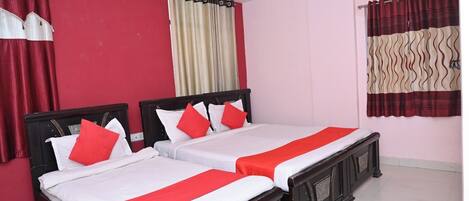 A hotel room with two beds, red and white bedding, a ceiling fan, and an air conditioning unit.