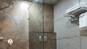 A bathroom with a glass-enclosed shower, a toilet, and a towel rack. - Hotel Star Inn (Jodhpur)