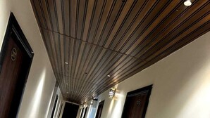 A long, narrow hallway with a wooden ceiling and black-framed doors on either side. - Hotel Star Inn (Jodhpur)