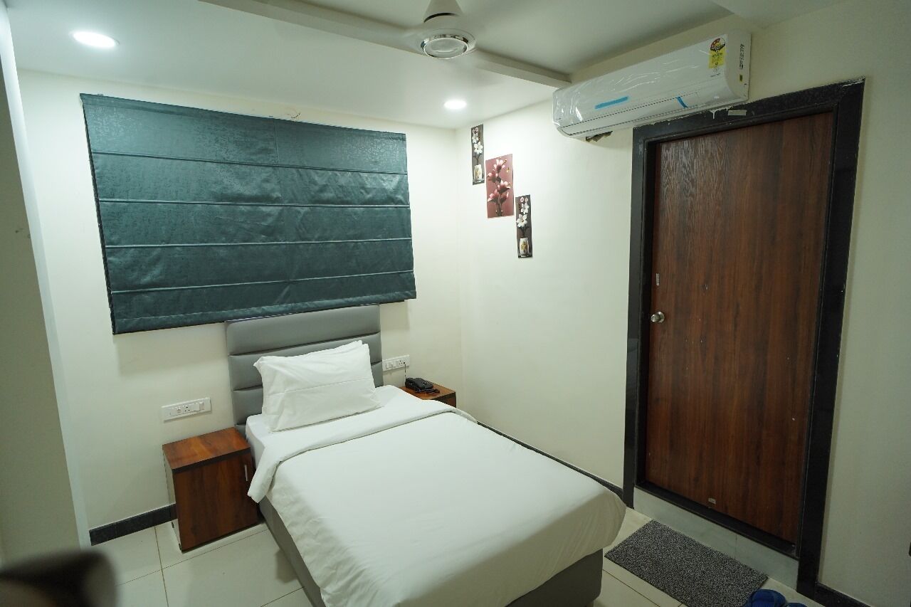 A bedroom with a bed, bedside table, wall-mounted air conditioner, and a door.