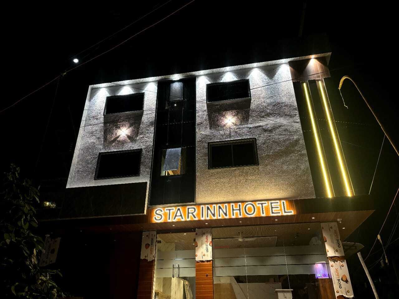 Un hotel con un letrero llamativo que dice "STAR INN HOTEL" y una fachada moderna con ventanas iluminadas.