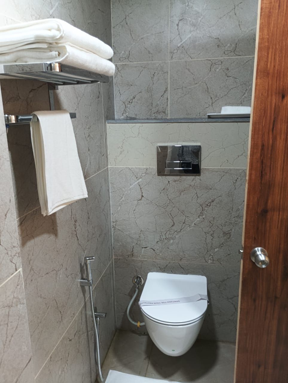 A small, modern bathroom with a toilet, a shower, and a towel rack.