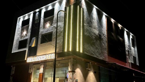 A hotel with a modern facade, illuminated signage, and a prominent vertical light feature. - Hotel Star Inn (Jodhpur)