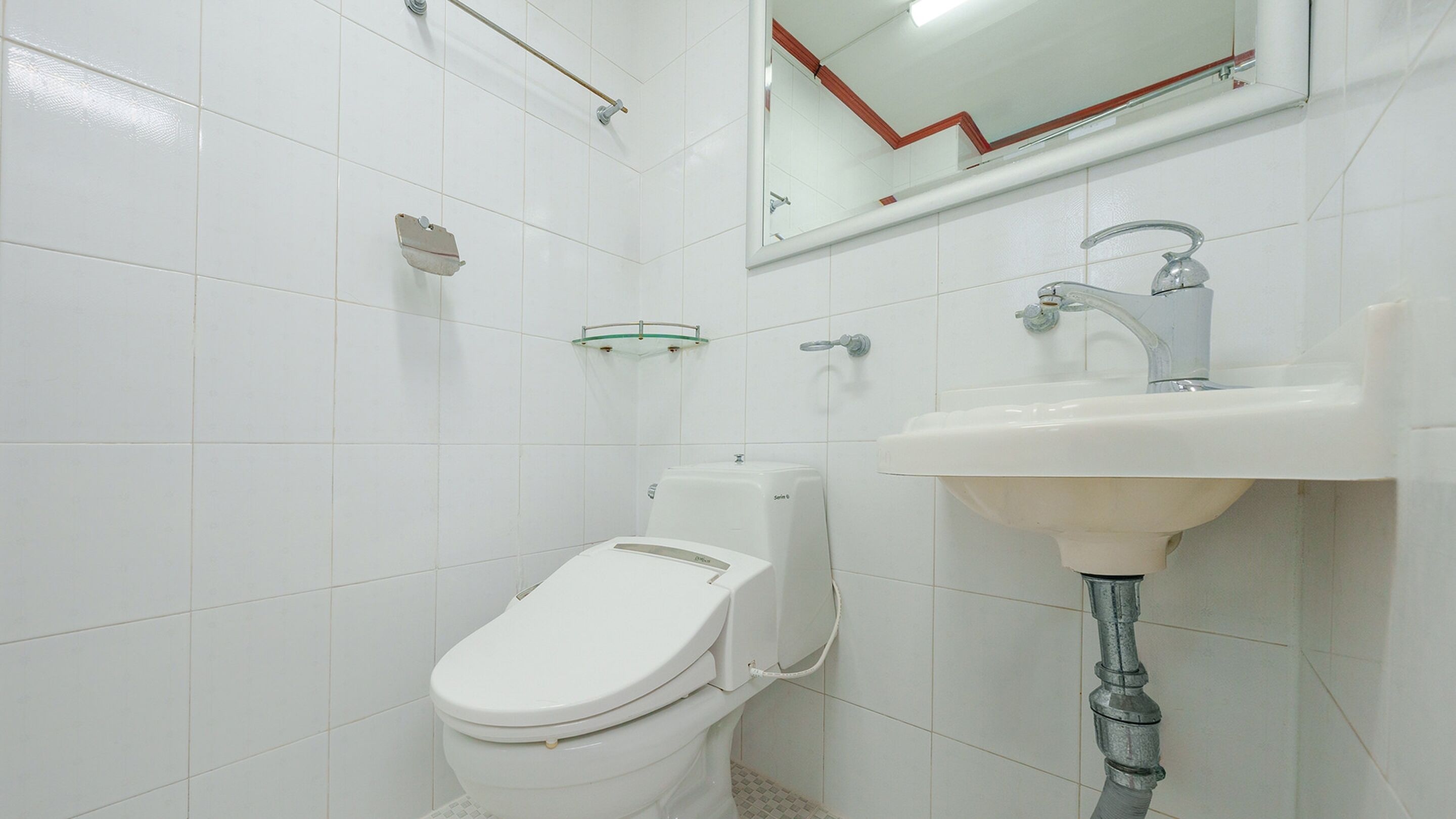 Ein kleines, weißes Badezimmer mit Toilette, Waschbecken und Spiegel.