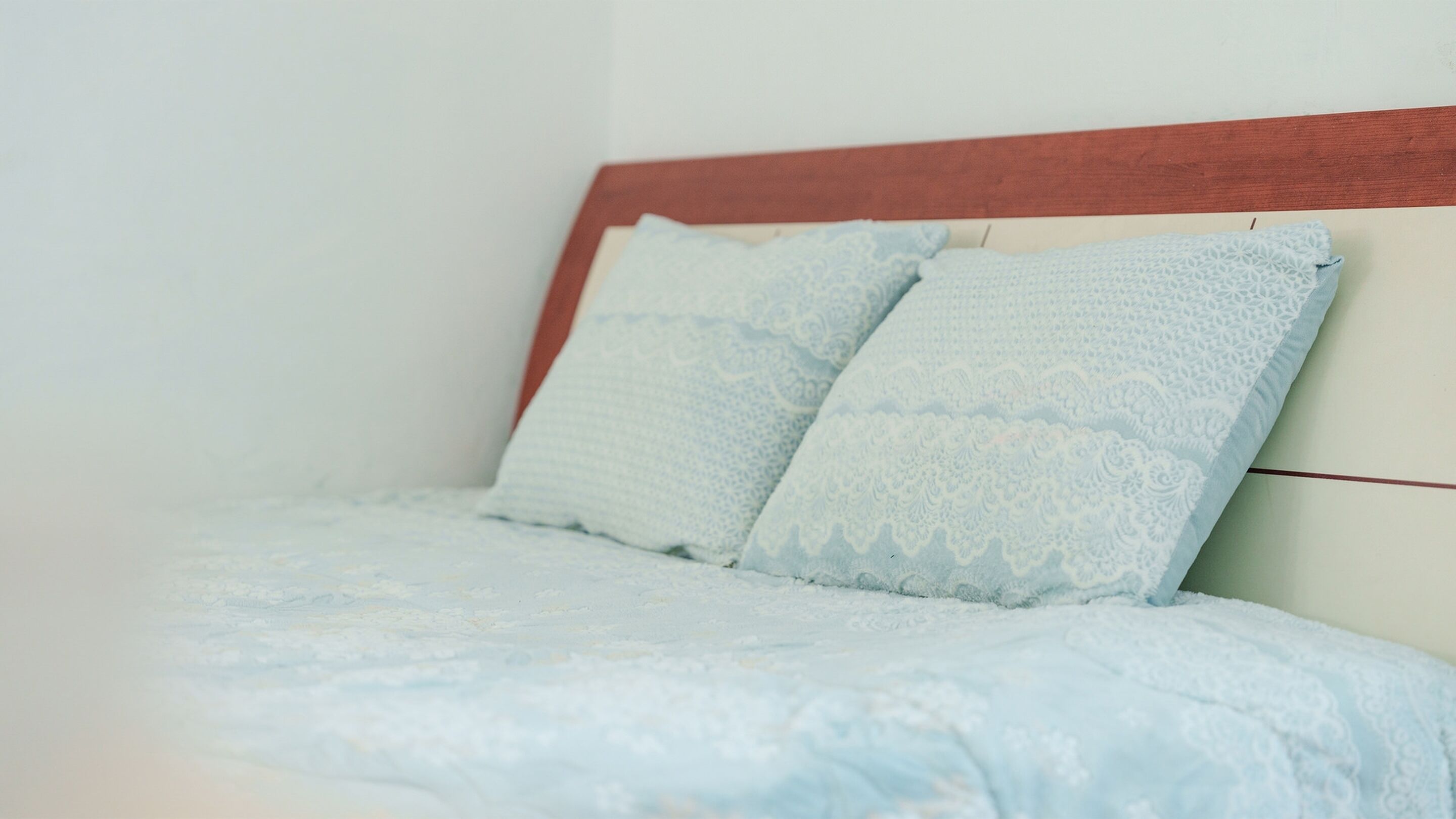 Un lit avec une tête de lit blanche et deux oreillers à motifs bleu clair.