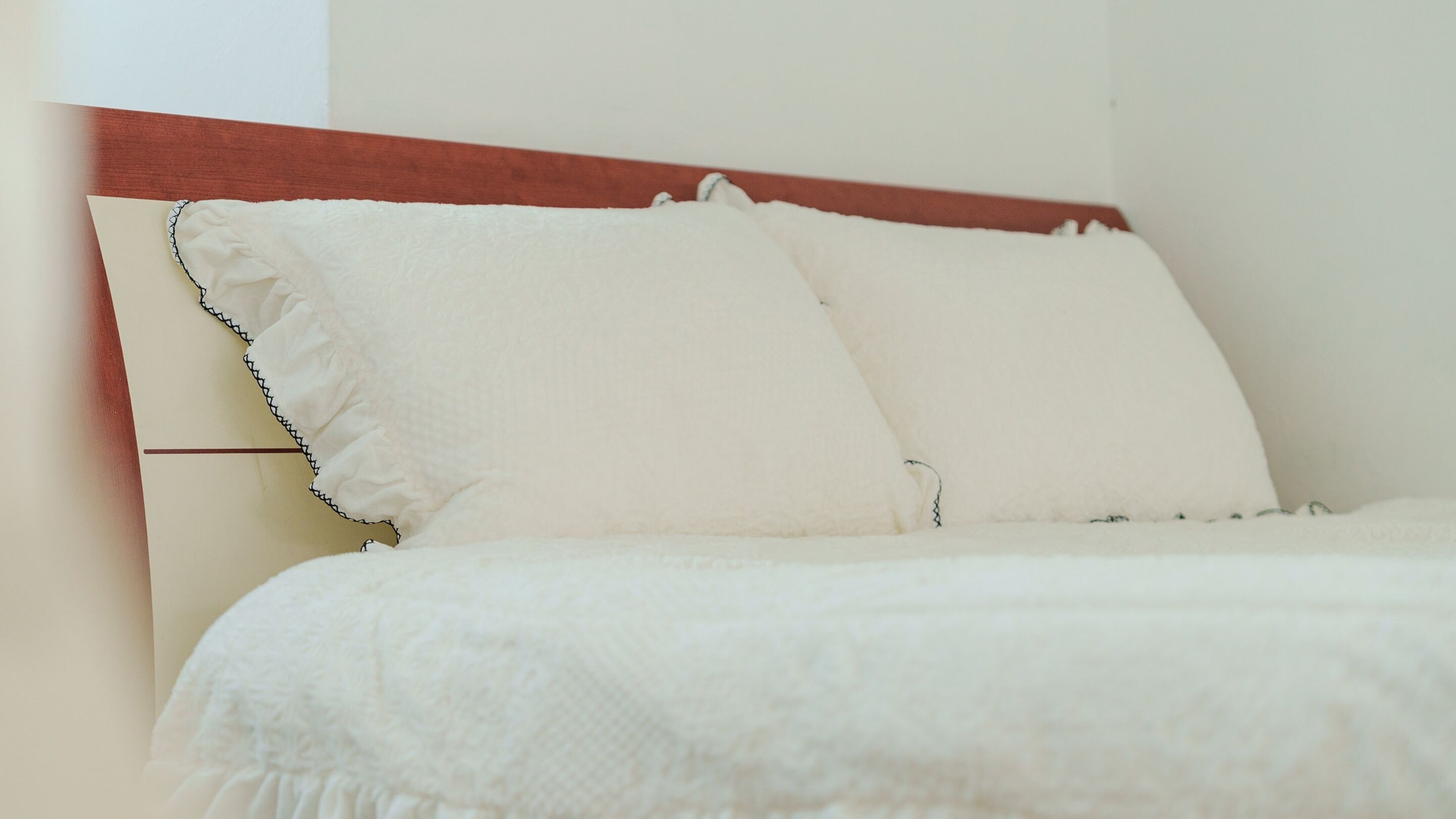 Un lit avec une literie blanche et une tête de lit en bois.