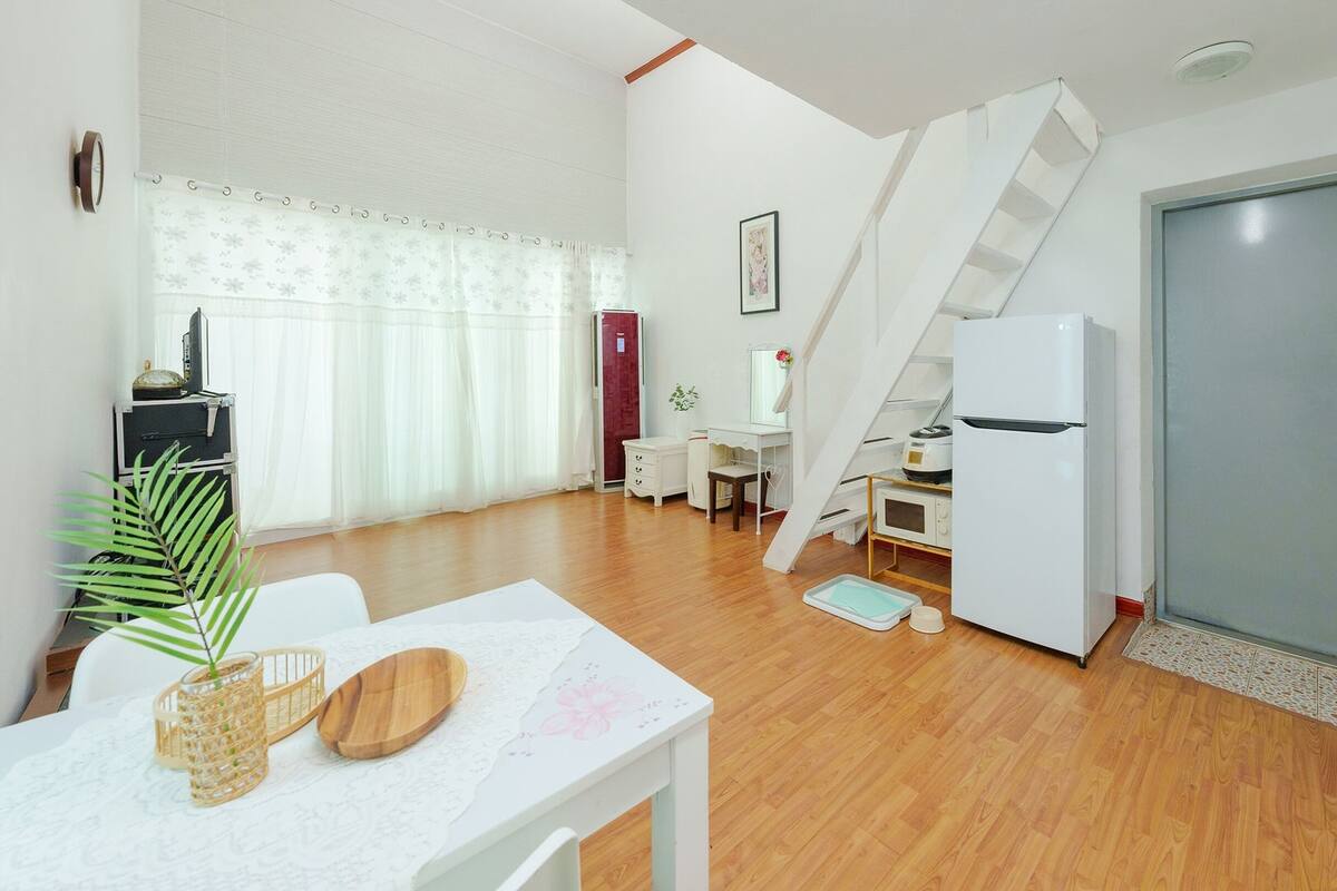 Un espacio habitable compacto con comedor, kitchenette y una escalera que conduce a un nivel superior.
