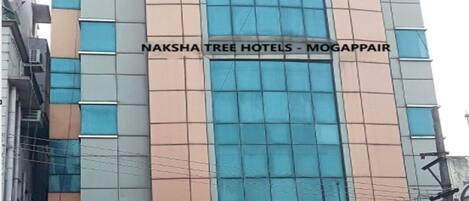 A hotel building with a sign reading "Naksha Tree Hotels - Mogappair".