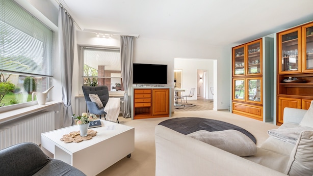 Een moderne woonkamer met een flatscreen televisie, een bank, een salontafel en een kast met glazen deuren.