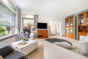 Ein modernes Wohnzimmer mit Flachbildfernseher, einer Couch, einem Couchtisch und einer Vitrine.