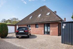 Ein Haus mit einem Auto auf der Einfahrt, einer Garage und einem Geräteschuppen.