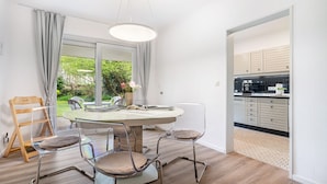 Een moderne keuken met witte kasten, een zwart aanrecht en uitzicht op groen.