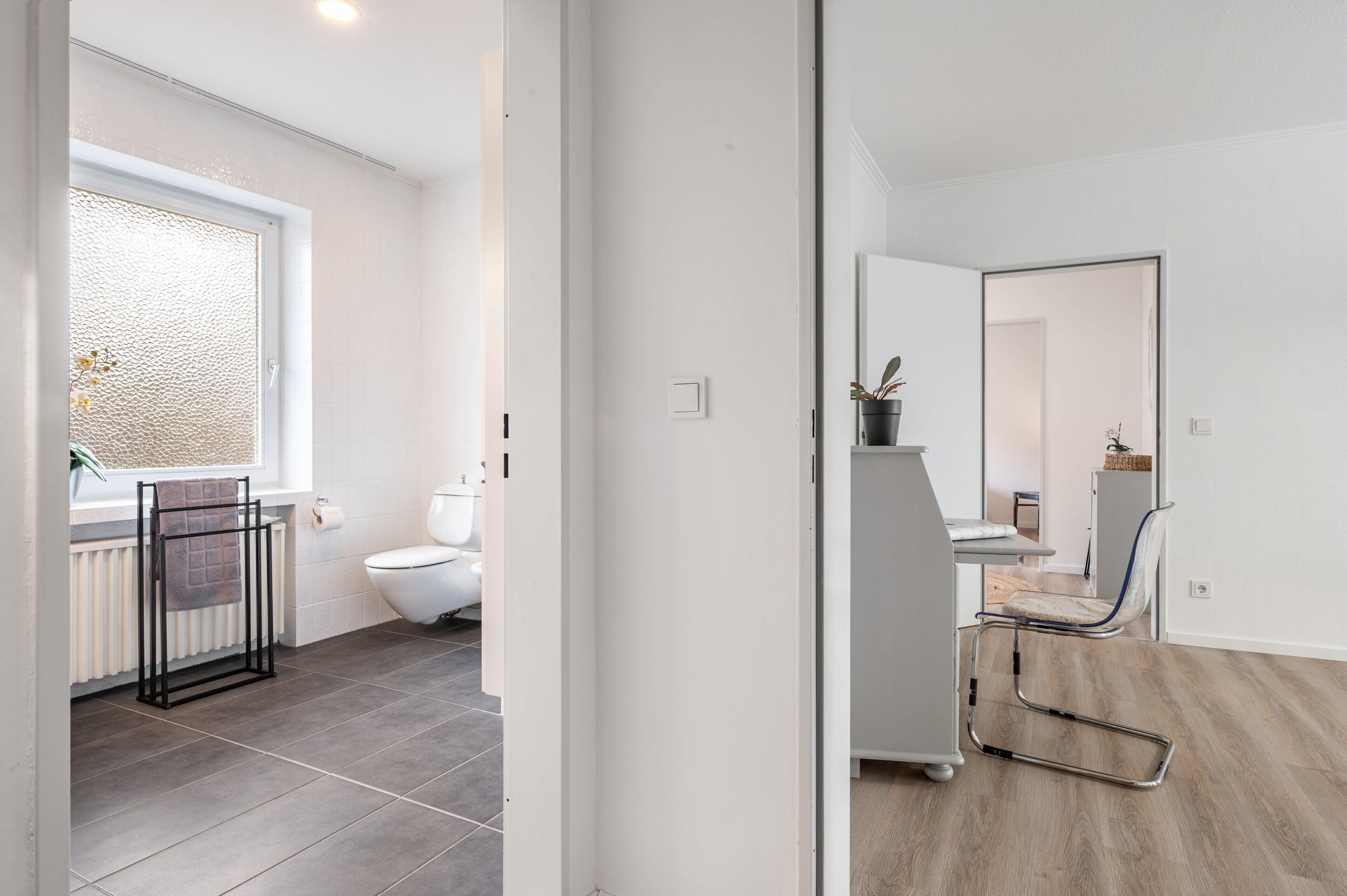 A modern bathroom with a toilet, a towel rack, and a window with a view.
