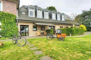 A two-story house with a sloped roof, a front porch, and a bicycle parked outside.