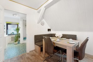 Un espace repas moderne avec une table en bois, des bancs rembourrés et une plante en pot.
