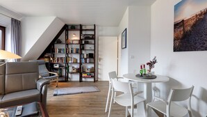 En stue med sofa, spisebord med stole, reol og trappe.