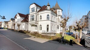 Eine Straße mit einer Reihe weißer Gebäude, blauem Himmel und einem geparkten Auto.