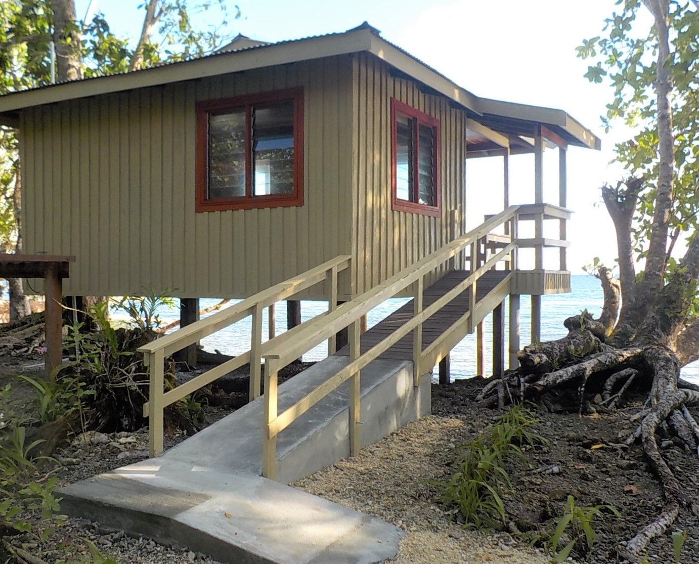 A wooden cabin with a concrete staircase leading up to a deck.