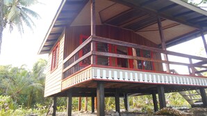Una casa de madera con balcón, rodeada de vegetación tropical.