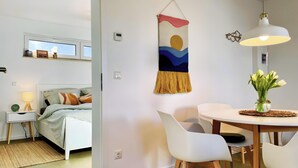 A modern bedroom with a bed, bedside table, lamp, and a view of the outdoors. - Apartment 'Boddenbude Lubmin' with Wi-Fi (Lubmin)