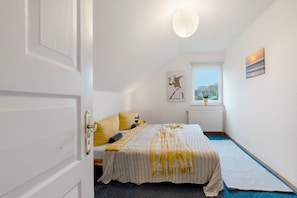 Ein Schlafzimmer mit Bett, Fenster, Heizkörper und einem Bild an der Wand.