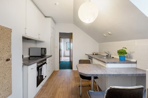 A modern kitchen with white cabinets, a microwave, a sink, and a dining area with chairs. - Holiday Home 'Hamdorf' with Private Terrace, Shared Garden and Wi-Fi (Hamdorf)