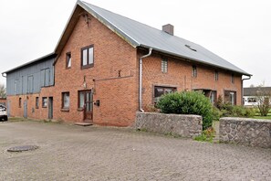 Ein Gebäude aus Backsteinen mit geneigtem Dach, einer Garage und einem gepflasterten Einfahrt.