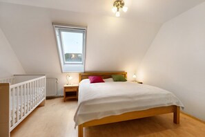 Quarto com cama de madeira, berço, janela e luminária no teto.