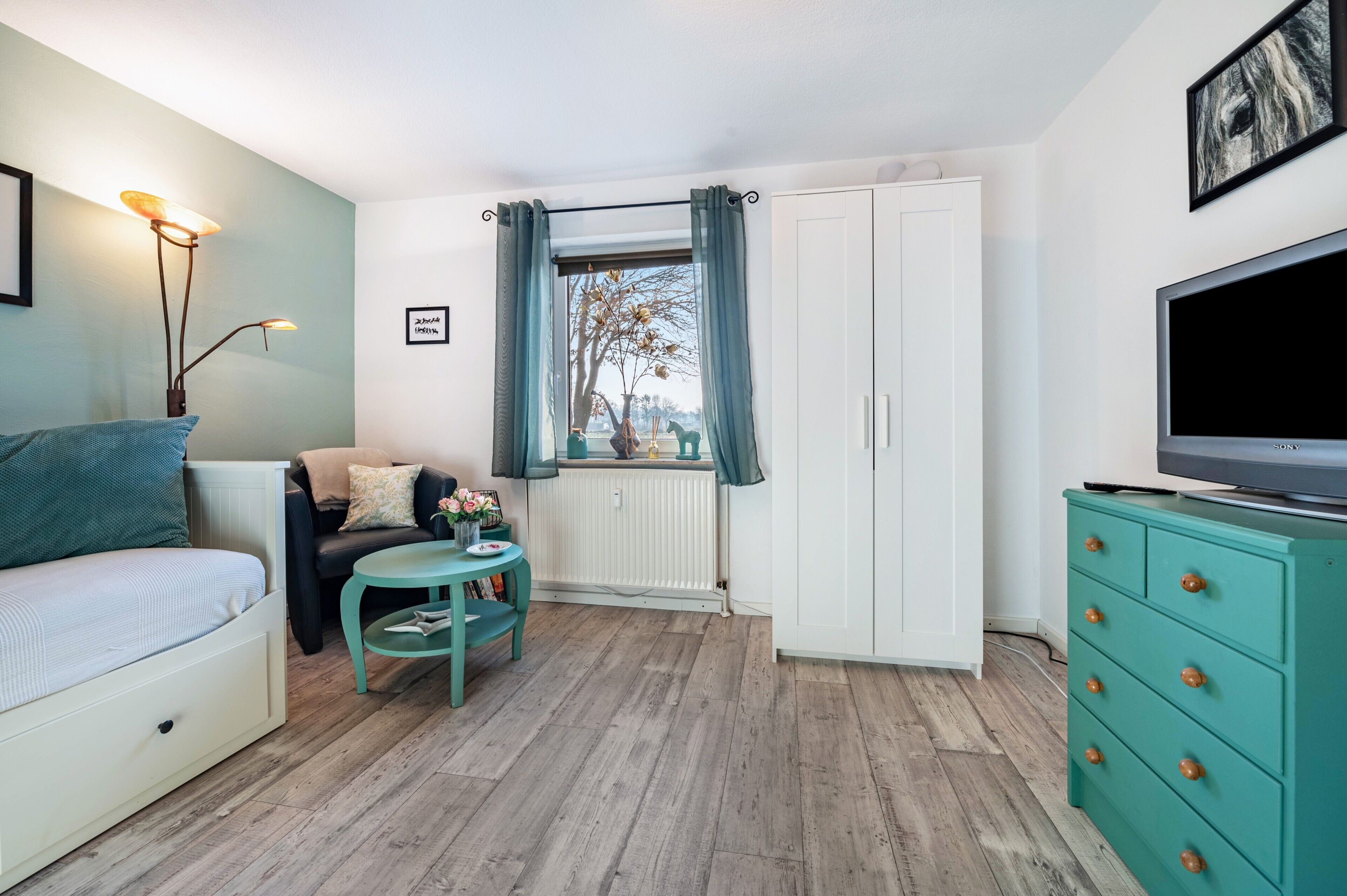 Un espacio habitable compacto con un sofá, una mesita con un florero, un televisor y un mueble.