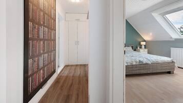 Ein Schlafzimmer mit Dachfenster, einem Bücherregal und einem Bett mit gemustertem Überwurf.